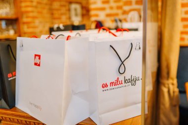 Riga, Letonya - 27 Mart 2025 - Beyaz Illy kahve hediye paketleri kırmızı ve siyah saplı ahşap bir tezgahta sergileniyor..