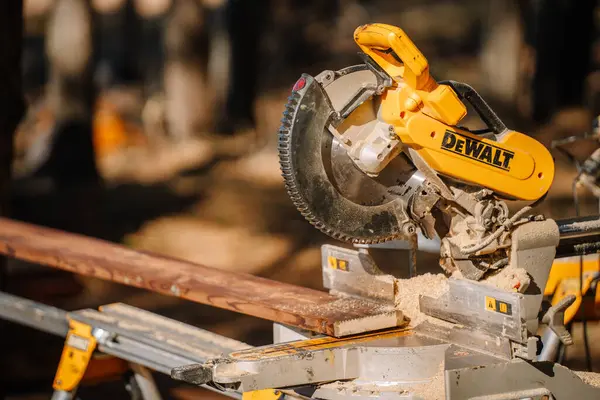Salacgiva, Letonya - 27 Mart 2025 - Doğal ışık altındaki bir inşaat sahasında bulunan ahşap ve talaşlı DeWalt dairesel metresinin yakın çekimi.