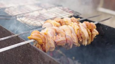 Çiğ terbiye edilmiş tavuk parçaları mangal kömürü üzerinde şişlenir ve kızartılır. Görünür bir duman yükselir ve açık havada mangal yaparken görüntülenir..