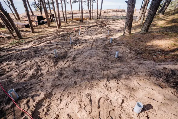 Kumsal yakınlarındaki ahşap bir yürüyüş pisti ya da platform için hazırlanmış metal vida yığını temelleri olan kumlu orman şantiyesi.