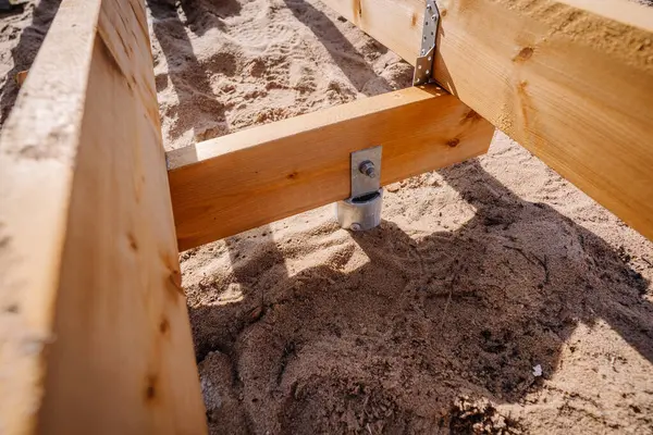 Açık hava inşaat projesinin bir parçası olan kumlu toprağa demirlenmiş ahşap tahta kaldırım destek iskeletinin yakın çekimi..