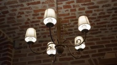 Tuğla bir tavana monte edilmiş beş lamba ile zarif bir klasik avizeye yakın çekim, sıcak ve klasik bir ortam yaratır..
