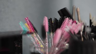 Renkli tek kullanımlık kirpik fırçaları ve hortlaklar güzellik salonundaki konteynırlara yerleştirilmiş. Çeşitli tonlar ve dokular hijyen ve güzellik araçlarını vurguluyor.