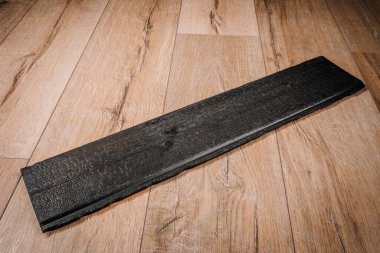 Görünür düğümleri ve kömürleşmiş dokusu olan tek bir parça yanmış ahşap panel yanmış, kırsal bir kaplama sergiliyor..