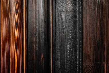 Doğal tahıl ve işçiliği vurgulayarak, kömürleşmeden cilalanmaya kadar benzersiz doku ve tonlarını gösteren çeşitli yanık ahşap tahtaların yakın çekimi.