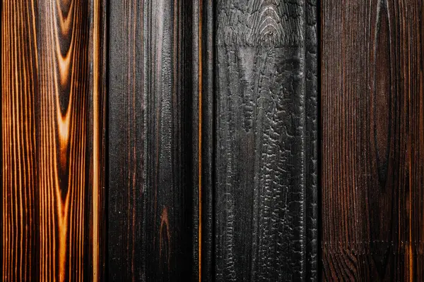 Doğal tahıl ve işçiliği vurgulayarak, kömürleşmeden cilalanmaya kadar benzersiz doku ve tonlarını gösteren çeşitli yanık ahşap tahtaların yakın çekimi.