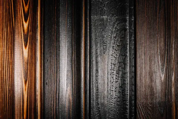 Doğal tahıl ve işçiliği vurgulayarak, kömürleşmeden cilalanmaya kadar benzersiz doku ve tonlarını gösteren çeşitli yanık ahşap tahtaların yakın çekimi.