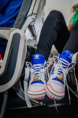 İstanbul, Türkiye - 19 Şubat 2022 - Yaratıcı göz, burun ve diş tasarımları ile benzersiz Adidas spor ayakkabıları bir uçak kabininde yolcu ayaklarına takıldı