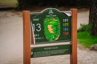 Belek, Türkiye - 25 Şubat 2025 - PGA Pines kursunun 13. deliğindeki ayrıntılı tabela mesafeleri, yerleşim yerlerini ve Rugged Valley adlı deliğin tanımını gösteriyor
