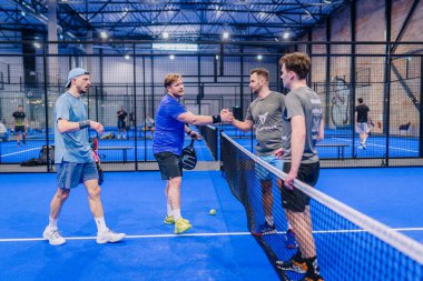 Riga, Letonya - 5 Nisan 2025 - Padel turnuvası sırasında sahada sportmenlik ve arkadaşlığı gösteren iki Padel takımı kalede el sıkıştı.