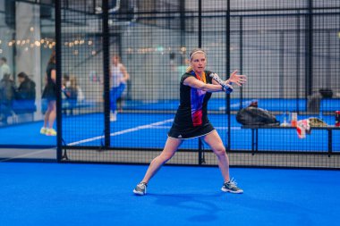 Riga, Letonya - 5 Nisan 2025 - Kadın padel oyuncusu, kapalı bir padel turnuvasında oynanan ön atış için hazırlanıyor..
