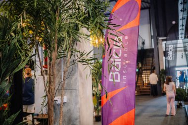 Riga, Letonya - 5 Nisan 2025 - Balcia Sigorta tanıtım pankartı, bir padel turnuvası sırasında arka planda yeşillik ve izleyicilerle çevrili bir yerde duruyor..