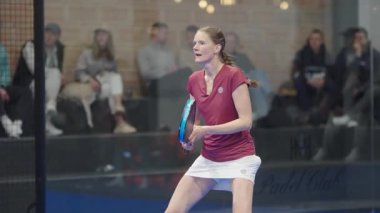 Riga, Letonya - 5 Nisan 2025 - Padel turnuvası maçında gülümseyen ve yumruğunu zaferle kaldıran bayan sporcu bir puanı kutluyor. Ağır çekimde çekilmiş bir video..