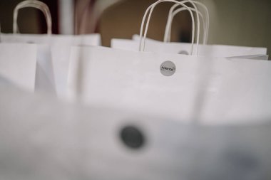 Türkiye, Belek - 28 Şubat 2025 - Adenta logosu etiketleri ve saplı beyaz kağıt hediye çantaları yakın bir şekilde düzenlenmiştir..