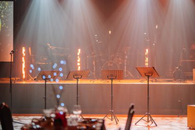 Valmiera, Letonya - 13 Aralık 2024 - Müzik standları, mikrofonlar, enstrümanlar ve VU 'nun 20. yıl dönümü kutlamaları için bir şölen salonunda sahne.