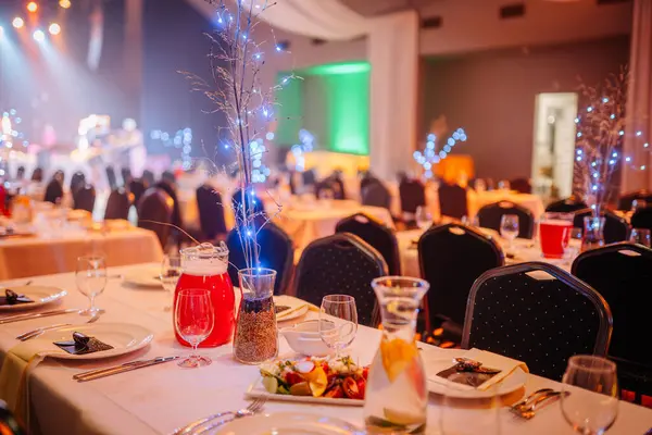 Valmiera, Letonya - 13 Aralık 2024 - VU 20. yıldönümü için verilen ziyafet salonu şenlik masaları, tabaklar, içecekler, salata ve ışıldayan ışıklarla şık bir kutlama atmosferi yarattı..