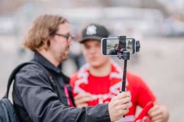 Riga, Letonya - 12 Nisan 2025 - Açık havada bir video röportajı kaydeden bir akıllı telefona yakın çekim sırasında telefon ekranında görünen gazeteciyle.