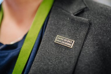 Riga, Letonya - 12 Nisan 2025 - Üzerinde yeşil bir halatla ne yaptığım hakkında hiçbir fikrim olmadığını belirten komik metal rozetli bir takım elbisenin yakın çekimi