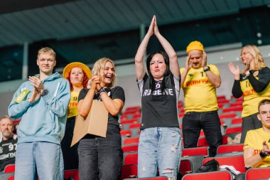Riga, Letonya - 12 Nisan 2025 Tribünlerde tezahürat yapan ve alkışlayan heyecanlı florbol taraftarları, takımlarını spor sahasında neşe ve enerjiyle destekliyor..