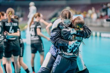 Riga, Letonya - 12 Nisan 2025 - Kadın florbol oyuncuları maçtan sonra sahada duygusal zaferlerini neşeyle kucaklayarak kutladılar.