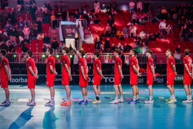 Riga, Letonya - 12 Nisan 2025 - Kırmızı üniformalı Floorball takımı, arka planda seyircinin olduğu kapalı spor salonundaki florball finalleri sırasında sırada bekliyor..