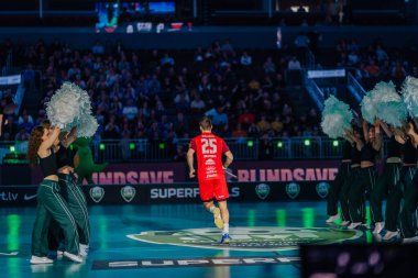 Riga, Letonya - 12 Nisan 2025 - Floorball oyuncusu florball finalleri sırasında arenaya çıkıyor, canlı ışıklar ve kalabalık enerjisi ile karşılanıyor.