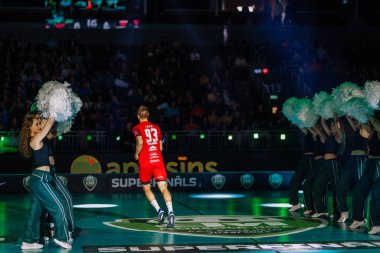 Riga, Letonya - 12 Nisan 2025 - Floorball oyuncusu ponpon kızları, dramatik ışıklar ve enerjik atmosferli atmosferli ponpon kızlar tarafından çevrili finallerde arenaya girer..