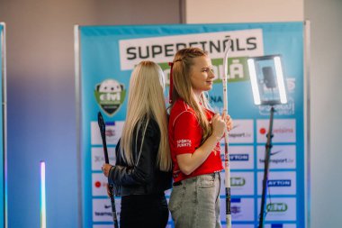 Riga, Letonya - 12 Nisan 2025 FBK Valmiera formalı gülümseyen genç kadın 360 video kabininde poz veriyor..