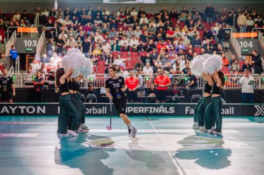 Riga, Letonya - 12 Nisan 2025 - Bir florbol oyuncusu florbol finalleri sırasında ponpon kız tünelinden büyük bir giriş yapar, taraftarlar ve medya o anı yakalar.