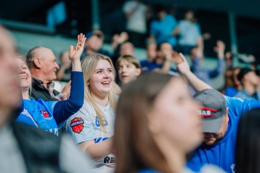 Riga, Letonya - 12 Nisan 2025 - Mavi formalı mutlu florbol taraftarları kalabalık bir salon arenasında zemin topu finallerinde tezahürat ve kutlama yapıyorlar..