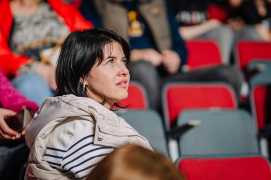 Riga, Letonya - 12 Nisan 2025 - Kadın seyircilerin arasında oturmuş, maçı ilgiyle izliyor ve kalabalık bir iç saha arenasına odaklanıyor..