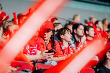 Riga, Letonya - 12 Nisan 2025 FBK Valmiera taraftarları enerji, takım kıyafeti ve köpük çubukları ile kırmızı tezahürat yaparak canlı bir kalabalık sahnesi yaratıyor..