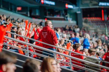 Riga, Letonya - 12 Nisan 2025 - Kırmızı FBK Valmiera takımlı taraftarlar canlı kapalı stadyum finallerinde canlı enerji ve takım ruhuyla dolu bir stadyumda tezahürat yapıyorlar..