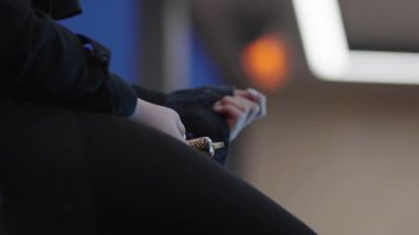 Riga, Letonya - 12 Nisan 2025 - Elinde mendil ya da bez tutan siyah elbiseli bir kadının yakın çekimi. Ilık ışık bokeh ile yumuşak arkaplan.