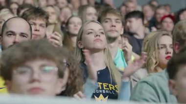 Riga, Letonya - 12 Nisan 2025 - Female floorball taraftarı alkışlıyor ve spor arenasında kalabalık tarafından çevrelenmiş, zemin topu finallerinde dikkatle maç izliyor..