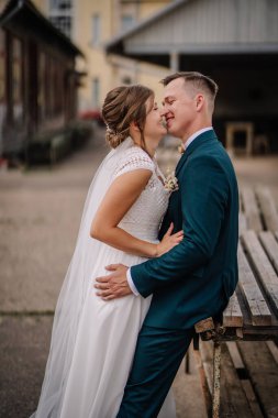 Gelin ve damat gülümser ve öpüşmek için eğilir, kırsal alanda neşeli ve samimi bir düğün anını paylaşır.