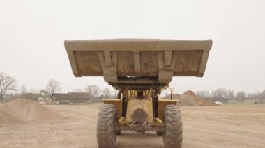 Valmiera, Letonya - 16 Nisan 2025 - Bir ön yükleyici kovasından çakıl boşaltır ve bir inşaat malzemesi deposunda yere çağlayarak akan bir akış yaratır..