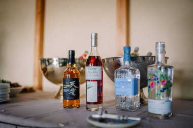 Sigulda, Letonya - 19 Nisan 2025 Viski, konyak ve cin içeren içki şişeleri rafine edilmiş bir iç mekan ortamında buz kovalarıyla bir masaya dizilmiştir..