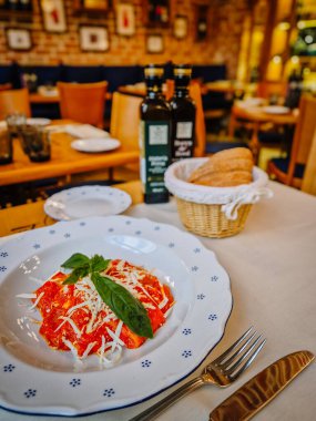Milan, İtalya - 10 Mart 2025 - Domates soslu lezzetli İtalyan ravioli, doğranmış peynir ve fesleğen, ekmek ve zeytinyağıyla servis edilir.