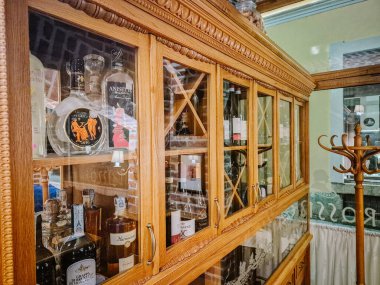 Milan, İtalya - 10 Mart 2025 - İtalyan grappa, şarap ve likörlerinin sergilendiği cam kapılı ahşap dolap.