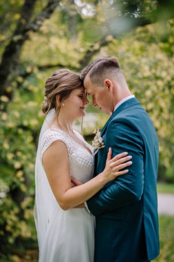 Gelin ve damat, alınları açık havada birbirine değen yakın dururlar. Düğün günlerinde aşkın duygusal ve barışçıl ifadesi.