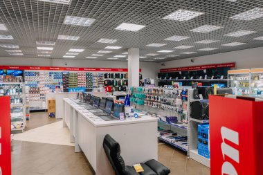 Valmiera, Letonya - 23 Nisan 2025 - Modern elektronik mağazası içi dizüstü bilgisayarlarla, aksesuarlarla ve iyi aydınlatılmış perakende alanında düzenlenmiş çeşitli teknolojik gereçlerle dolu.