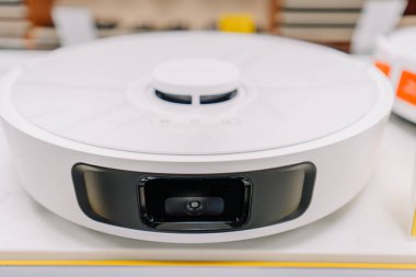Valmiera, Letonya - 23 Nisan 2025 - Akıllı ev seyrüsefer ve temizlik için tasarlanmış ön yüzlü kamera ve sensör sistemiyle beyaz bir robotik elektrikli süpürgeye yakın çekim.