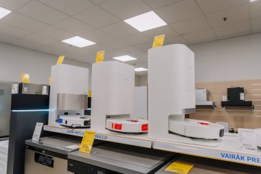 Valmiera, Letonya - 23 Nisan 2025 - Bir elektronik mağazasında demirleme istasyonları sergilenen modern robot vakum temizleyicileri, yukarıda fiyatlandırma etiketleri ve aydınlatma ile raflarda sergileniyor.