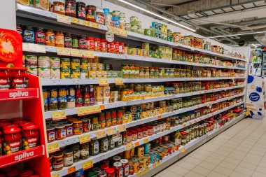 Valmiera, Letonya - 23 Nisan 2025 - Sosu, sebzesi, yayılımı ve baharatı da içeren çok çeşitli konserve ve salamura yiyeceklerle dolu bir market koridoru.