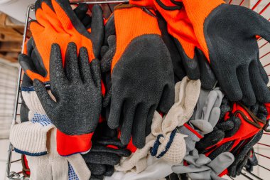 Valmiera, Letonya - 23 Nisan 2025 - Siyah kauçuk kaplama, kırmızı güvenlik ve örgü işlemeli eldiven yığını.