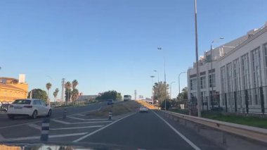 Malaga, İspanya - 24 Ocak 2025 - Güneşli bir öğleden sonra açık gökyüzü, yön işaretleri ve ışık trafiğiyle Malaga 'da bir otoyol çıkış rampasından geçmek.
