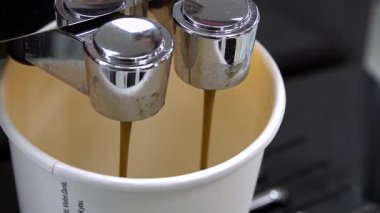 Valmiera, Letonya - 23 Nisan 2025 - Kâğıt bir fincana taze espresso dolduran kahve makinesinin yakın çekimi, zengin kahve akışını ve krom detaylarını gösteriyor.