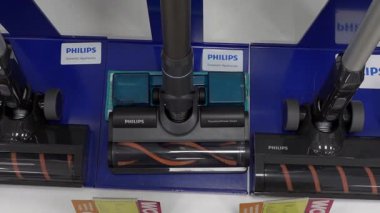 Philips 'in kablosuz elektrik süpürgesi kafalarının turuncu dönen fırçalarla yakın plan görüntüleri, elektronik perakende satış ayarlarında bir mağaza rafında sergileniyor. Valmiera, Letonya - 23 Nisan, 2025 - 