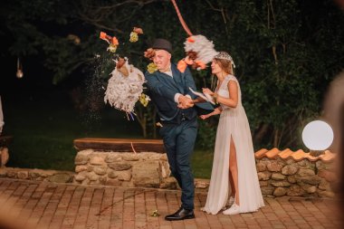 Bir damat havanın ortasında şenlikli bir pinatayı ezerken gelin canlı bir düğün kutlaması sırasında, çiçek ve konfeti serpiştirirken.